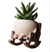 Ceramic planter with a smiling face on a wooden rocking chair