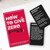 Red book titled 'How to Give Zero F**ks' with two black cards on a white surface.