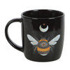 Black ceramic mug with a forest bee design, including a crescent moon and stars, printed on the front.