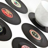A collection of vinyl record-shaped coasters with various retro design labels, displayed on a surface.